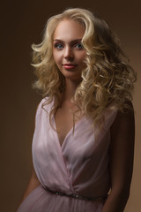Naklejka premium portrait of beautiful curly blonde woman in gorgeous pink dress looking at camera