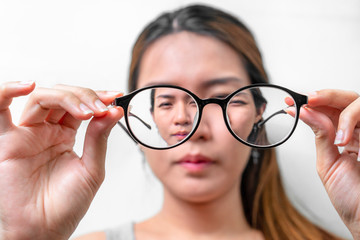 Asian woman holding glasses on white background, Selective focus on glasses , myopia and eyesight problem concept. - obrazy, fototapety, plakaty