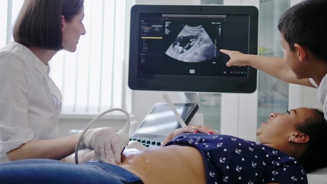 Pregnant woman and her son on utltrasonographic examination at hospital