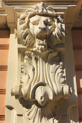 Lion stone head carved on house facade close up view 