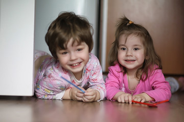 Naklejka premium Children boy and girl crawling on the floor. The children are smiling and lying on the floor. Children are playing at home.
