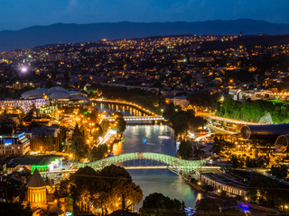 Fototapeta na wymiar Beautiful cityscape with Bridge of Peace over Kura river in Tbilisi, Georgia, illuminated in the night.