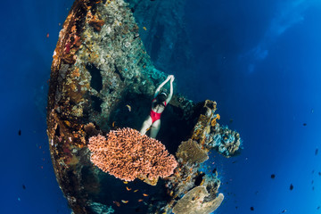 Woman free diver swimming at wreck ship. Freediving in blue ocean in wreck