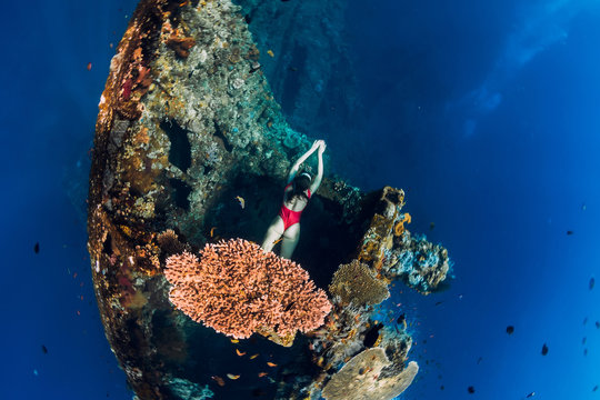 Woman free diver swimming at wreck ship. Freediving in blue ocean in wreck