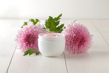 Cream. cosmetics for face and body. Pink cream and flower in a white jar on a white wooden table