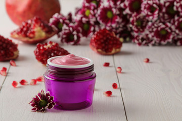 Obraz na płótnie Canvas Cream. cosmetics for face and body. Pink cream and flower in a purple jar on a white wooden table.