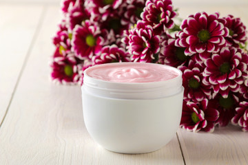 Obraz na płótnie Canvas Cream. cosmetics for face and body. Pink cream and flower in a white jar on a white wooden table