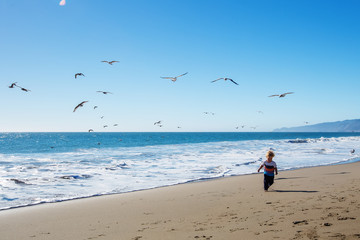 Happy and free boy on the beach with seagulls