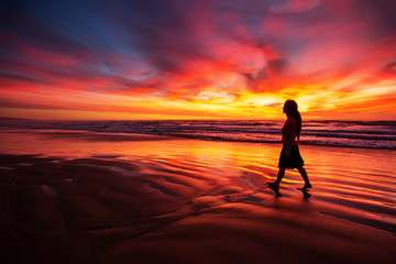 woman walking alone on the beach in the sunset