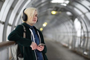 Young girl listens to music in big headphones in the subway