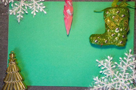 New Year's toys in the form of green Santa Claus boots and other toys on a green background with white snowflakes. Behind black background. Fonk both for cards and congratulations..