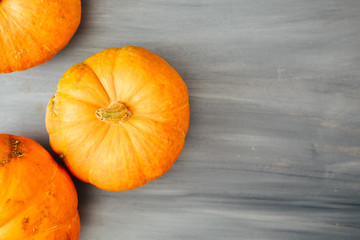 Fall Thanksgiving and Halloween pumpkins over gray wood table background shot from directly above Thanksgiving and Halloween concept. View from above. Top view. Copy space for text and design