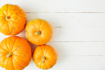 Orange pumpkins on white wooden background. Thanksgiving and Halloween concept. View from above. Top view. Copy space for text and design