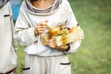 Beekeeper holding fresh honey and sweet fruits on the apiary, close-up view