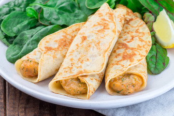 Savory crepe with shrimps and creamy dill sauce served with green leaves salad and lemon, horizontal, closeup