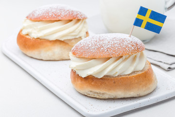Traditional swedish dessert Semla, also called Shrove bun, with almond paste and whipped cream filling, served with milk, horizontal