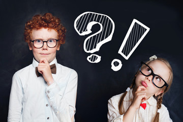 Smart cute thinking kids little girl and boy school student with question mark on chalkboard background. Brainstorming and idea concept