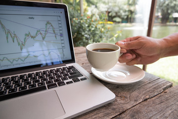 Trader man hand holding a cup of black coffee and analyze tactical move, strategy analysis of stock graph