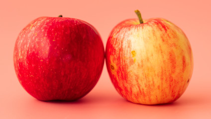Two red apples on a pink background