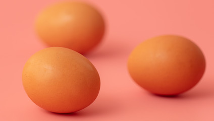 Three chicken eggs on a pink background