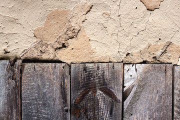 Old cob wall with cracked surface and old wooden boards
