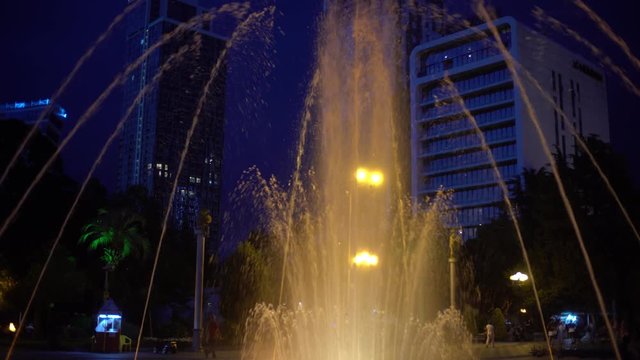 The illuminated fountain shimmers under the music in the evening in the city. Georgia, Batumi.