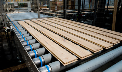 Production line of the wooden floor factory. CNC automatic woodworking machine.