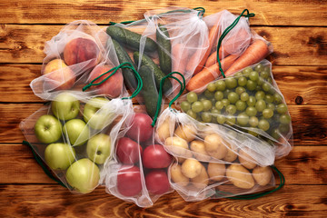 Fruits and vegetables in reusable eco-friendly bags on wooden background.Close-up. Zero waste shopping concept. Ecological concept. Refuse plastic. Stop pollution.