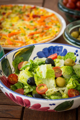 Small lettuce salad with pizza in background