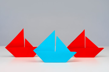 Paper boats stand on the table. Concept - The variety of approaches. Pluralism. The choice of direction. A large assortment. Multi-way development path. Variety of choice. Origami from paper.