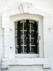 Fototapeta premium antique white window in a white brick frame and forged lattice, closeup