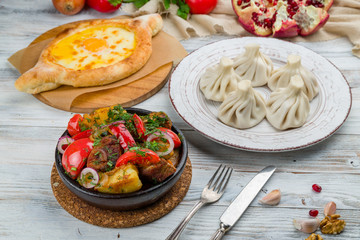 Ojakhuri, khinkali, khachapuri on light wooden table, georgian kitchen.