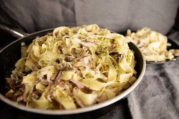 Italian fresh fettuccine pasta with Mushroom and greens in a pan on grey background. top view