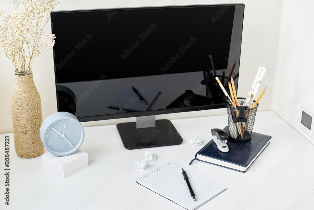 Wall mural Modern workspace background, front view. Mockup workplace with desktop, clock, office supplies and flower branch in a vase