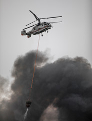 helicopter extinguishes a fire from a basket of water