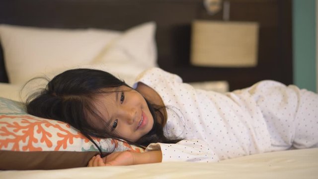 Asian child cute or kid girl sleep watch TV or television with smiling and happy fun for cartoon and relax on bed in bedroom at night on free time and holiday which causes ADHD or Hyperactive 4K