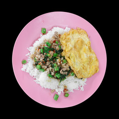 basil fried pork with omelet and white rice on pink dish for lunch or breakfast on street and spicy traditional with Thai food on black background isolated