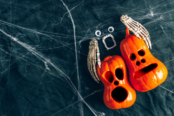 Halloween background, pumpkins with eyes and mouths cut out, Bony hands hugging a pumpkin ,Jack lamp, gloomy and dark atmosphere, stretched web in the background
