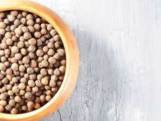 Allspice (Jamaica pepper) in a wooden cup on a gray background with copyspace