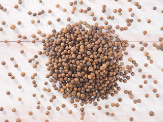 Allspice (Jamaica pepper) on a brown wooden background
