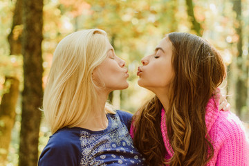 Friendly kiss. Girls friends kissing. Girlish friendship concept. Blonde and brunette walking in autumn park defocused background. Women kiss cute faces close up. Kiss me. Best friends forever