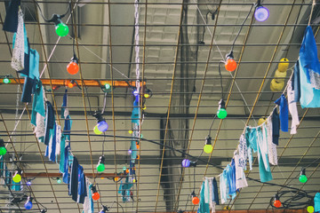 Obraz premium Street garland of light bulbs and multi-colored flags on the ceiling. Toned. Close-up. Interior.