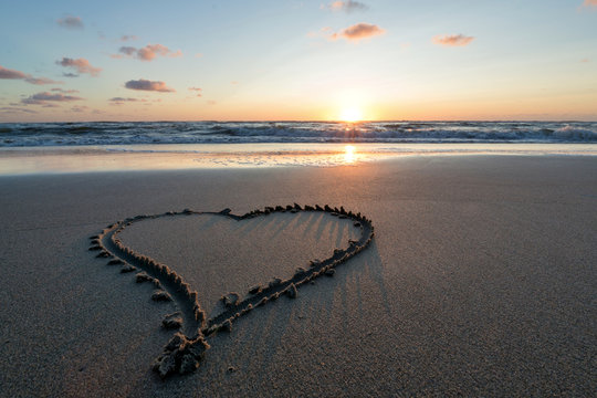 heart in the sand at sunset