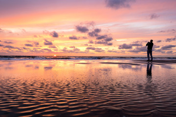 Fototapeta premium photographer at beach against sunset
