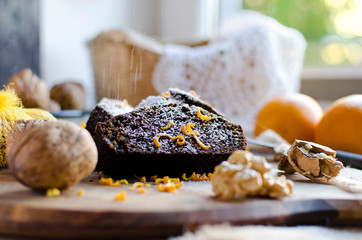 Chocolate cake with sugar, nuts and orange. Homemade brownie for dessert. Baked food in the kitchen. Close up.