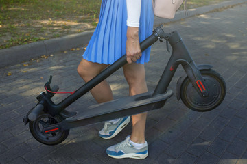 Close-up of a girl's hand holding a folded electric scooter