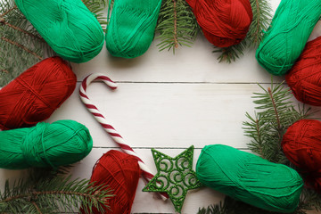 Fir tree branches and yarn threads on light wooden background. Christmas knitting concept