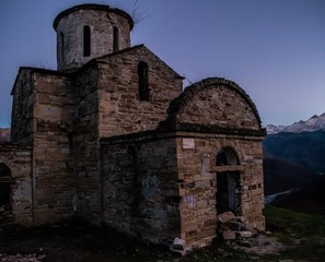 Fototapeta na wymiar old abandoned Senty church in front of Caucasus mountain range in Teberda, Russia