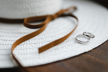 Wedding rings from the white gold on the white hat with brown tape