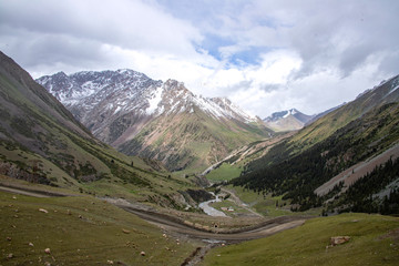 Serpentine mountain road in the valley between the hills covered with coniferous forest and the...